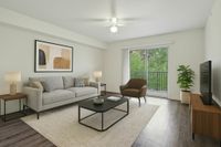 Chic living room with modern decor, cozy seating, large windows offering lush greenery views.