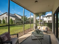 Inviting screened patio with modern outdoor seating and lush green views, perfect for relaxation in a serene neighborhood.
