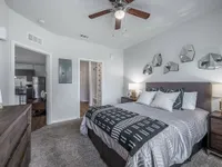 Elegant bedroom with modern decor, featuring geometric wall art and cozy bedding, adjacent to an open kitchen with stainless steel appliances.