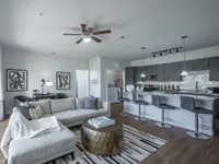 Modern open-concept living space with a sleek kitchen, stylish bar stools, and cozy sectional sofa, perfect for entertaining.