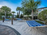 Relaxing outdoor oasis with striped hammocks nestled among palm trees on soft sandy grounds.