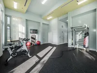 Bright and modern gym with state-of-the-art equipment, including exercise bikes, boxing bag, and resistance bands, complete with natural light and sleek interior design.