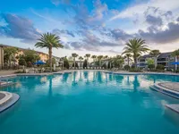Luxurious apartment poolside oasis with palm trees and sun loungers, offering a resort-like atmosphere.