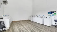 Modern laundry facility featuring multiple washing machines, sleek flooring, and convenient seating.