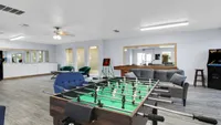 Inviting game room with sleek foosball table, comfortable seating, and modern arcade machine, perfect for entertaining and relaxation.