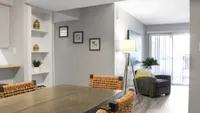 Chic and cozy living space featuring elegant wicker chairs, decorative shelving, and abundant natural light from large sliding doors.