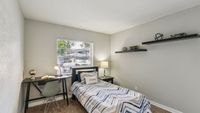 Inviting bedroom with modern décor featuring a cozy single bed, stylish desk, and sleek floating shelves, perfect for relaxation and productivity.