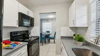 Chic kitchen view featuring white cabinets, modern appliances, and a peek into an inviting dining area with elegant table setting.