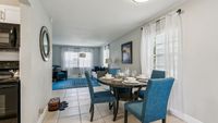 Charming open-concept dining and living area with elegant decor, featuring blue upholstered chairs, a cozy sofa, and ample natural light.