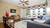 Inviting living room with chic decor, featuring a plush gray sofa, elegant wooden chair, and a stylish round coffee table accented with vibrant red vases.