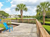 Charming lakeside view with wooden boardwalk, surrounded by lush greenery and palm trees, perfect for a serene retreat.