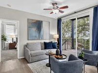Sophisticated living room with elegant decor, cozy seating, and large windows opening to a scenic balcony.