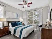 Inviting bedroom with elegant decor, soft lighting, and large window offering a scenic view, perfect for relaxation.