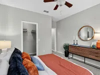 Elegant bedroom with stylish decor, featuring a cozy bed, vibrant pillows, modern dresser, and a walk-in closet.