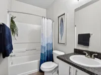 Modern bathroom with elegant design featuring a sleek countertop, stylish sink, and soothing blue shower curtain.