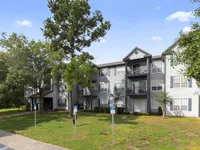 Charming apartment complex surrounded by lush greenery and modern architecture, offering serene living in a spacious, inviting environment.