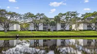 Charming apartment complex with lush greenery and serene water views, offering a peaceful and picturesque living environment.