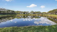 Tranquil lakeside view with lush green landscaping and serene reflections under a bright blue sky.