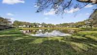 Charming pond view with lush greenery and clear blue sky, offering serene natural beauty in a residential community.