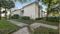 Charming residential building surrounded by lush greenery, featuring modern architecture and a peaceful walkway.