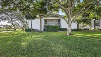 Charming apartment exterior surrounded by lush greenery and mature trees, offering a serene and inviting atmosphere.