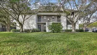 Charming apartment building facade with lush greenery and mature trees, offering a peaceful residential setting.
