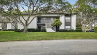 Charming apartment building surrounded by lush greenery and mature trees, offering a serene living environment.