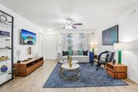 Bright and inviting living room with modern decor, featuring a cozy sofa, stylish armchairs, and elegant wooden furniture, complemented by a large window and artistic accents.