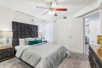 Luxurious bedroom with elegant bed, plush carpet, stylish ceiling fan, and abundant natural light through soft curtains.