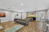 Modern community lounge with sleek gray seating, glass-top tables, and a vibrant dining area, perfect for social gatherings.