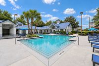 Luxurious apartment complex featuring a pristine outdoor pool surrounded by palm trees and stylish seating areas, ideal for relaxation and leisure.