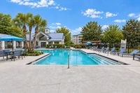 Inviting outdoor swimming pool area with lounge chairs, blue umbrellas, and lush greenery, perfect for relaxation and social gatherings.