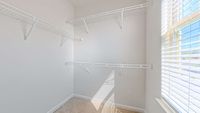 Bright and spacious walk-in closet with ample white shelving and natural light through large window.
