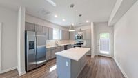 Modern kitchen with stainless steel appliances, sleek island, and elegant pendant lighting.