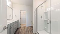 Modern bathroom with sleek glass shower, spacious vanity, elegant lighting, and walk-in closet access.