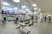 Modern fitness center with state-of-the-art equipment, well-lit interior, and scenic views through large windows.