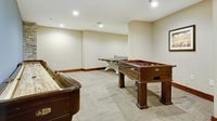 Luxurious game room featuring a shuffleboard table, foosball, and ping pong, perfect for leisure and entertainment.