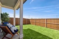 Charming backyard with lush green lawn, cozy seating area, and privacy fencing, perfect for outdoor relaxation.