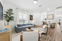 Modern open-concept living room with stylish decor, large window, and elegant dining area adjacent to a sleek kitchen.