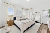Bright, serene bedroom featuring a luxurious bed, elegant mirror, and soft natural light accents, highlighting modern decor.