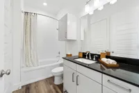 Elegant bathroom with sleek black countertop, modern fixtures, and stylish cabinetry, offering a spa-like ambiance.