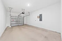 Spacious and versatile garage with pristine white walls, modern overhead door, and ample storage potential.