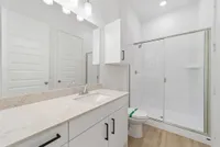 Modern bathroom featuring sleek white cabinetry, elegant granite countertop, and a spacious glass-enclosed shower.