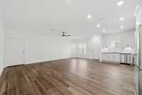 Spacious open living area with modern wood flooring, sleek kitchen cabinetry, and abundant natural light.