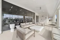 Luxurious outdoor living space with modern lounge seating, glass walls offering stunning views, and a sleek ceiling fan.
