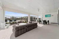 Luxurious outdoor living space featuring a stylish seating area with plush sofas, elegant dining setup, ceiling fan, and a view of the serene swimming pool.