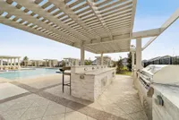 Luxurious outdoor area featuring a modern pergola, sleek stone countertops, and a sparkling pool with private cabanas.
