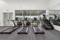 Modern fitness center showcasing state-of-the-art treadmills and step machines, overlooking a serene outdoor seating area.