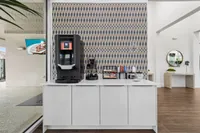 Modern lobby area with stylish wallpaper and a sleek coffee station, inviting atmosphere for relaxation.