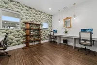 Modern home office space with stylish floral wallpaper, elegant shelving, and dual workstations with chic seating.